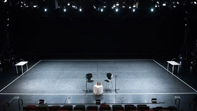Darkened Empty Theater stage with two chairs in the center