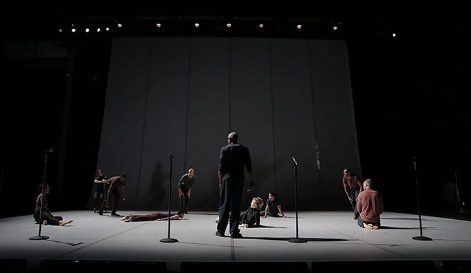 Dark stage with dancers standing and lying down