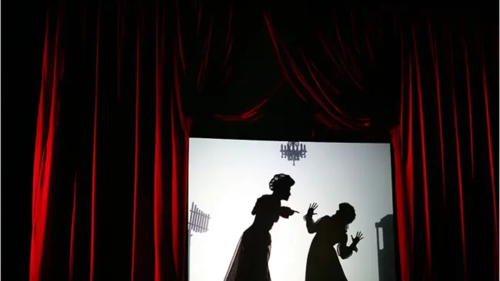 A silhouette of two people arguing is framed by red velvet curtains