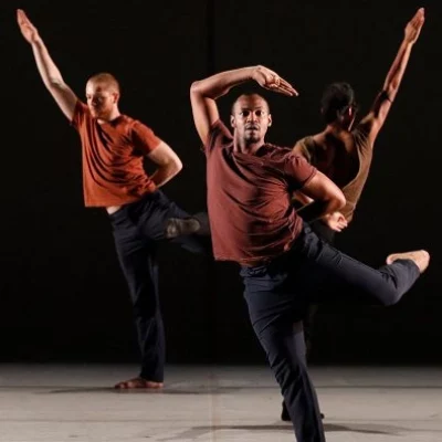 Dancers strike dynamic angular poses in front of a black background