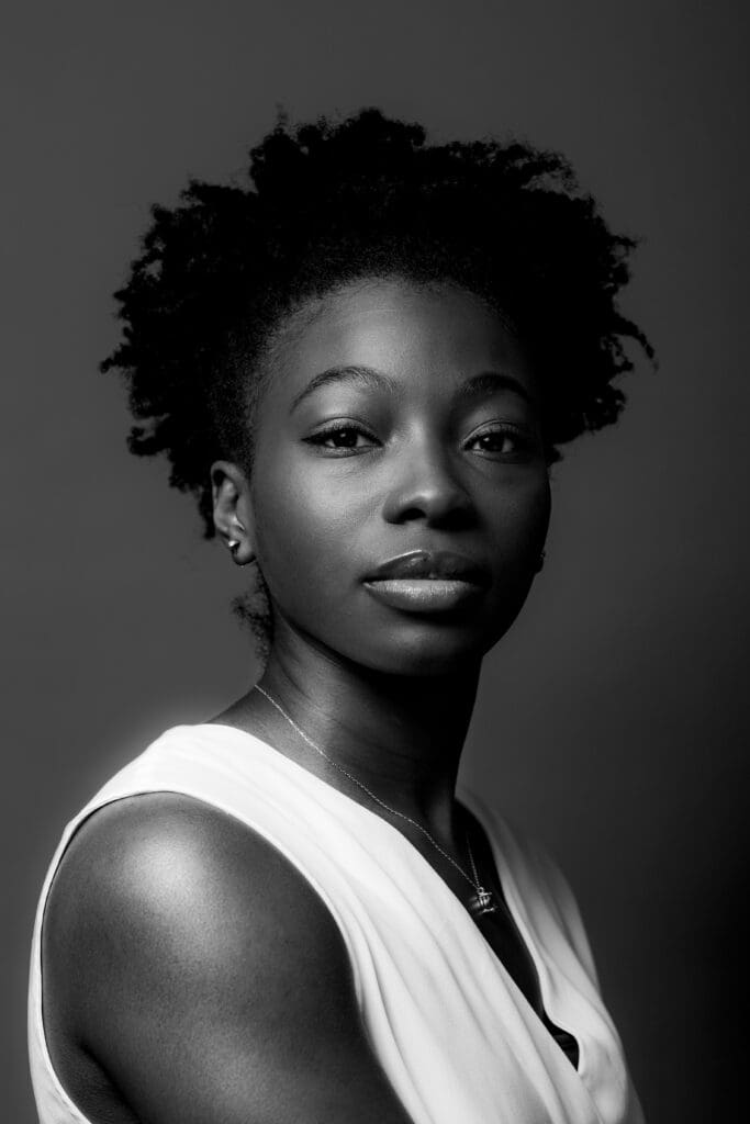 Black and white portrait photo of Danielle Marshall. They are wearing a white top with a small metal necklace.