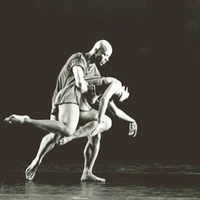 Black and white photo of a dancer, who is carrying the frail limp body of another